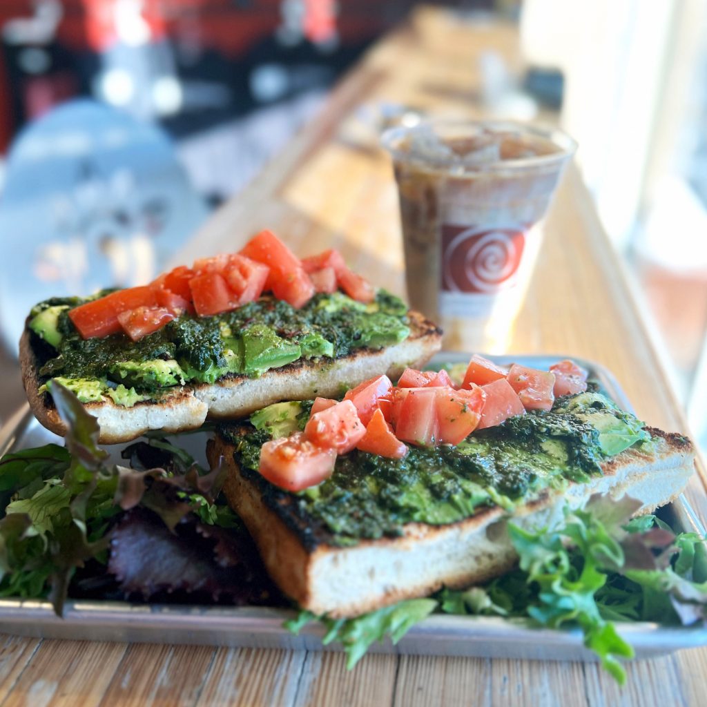 Avocado toast with pesto and fresh tomatoes served with iced coffee at Longfellow’s Coffee.