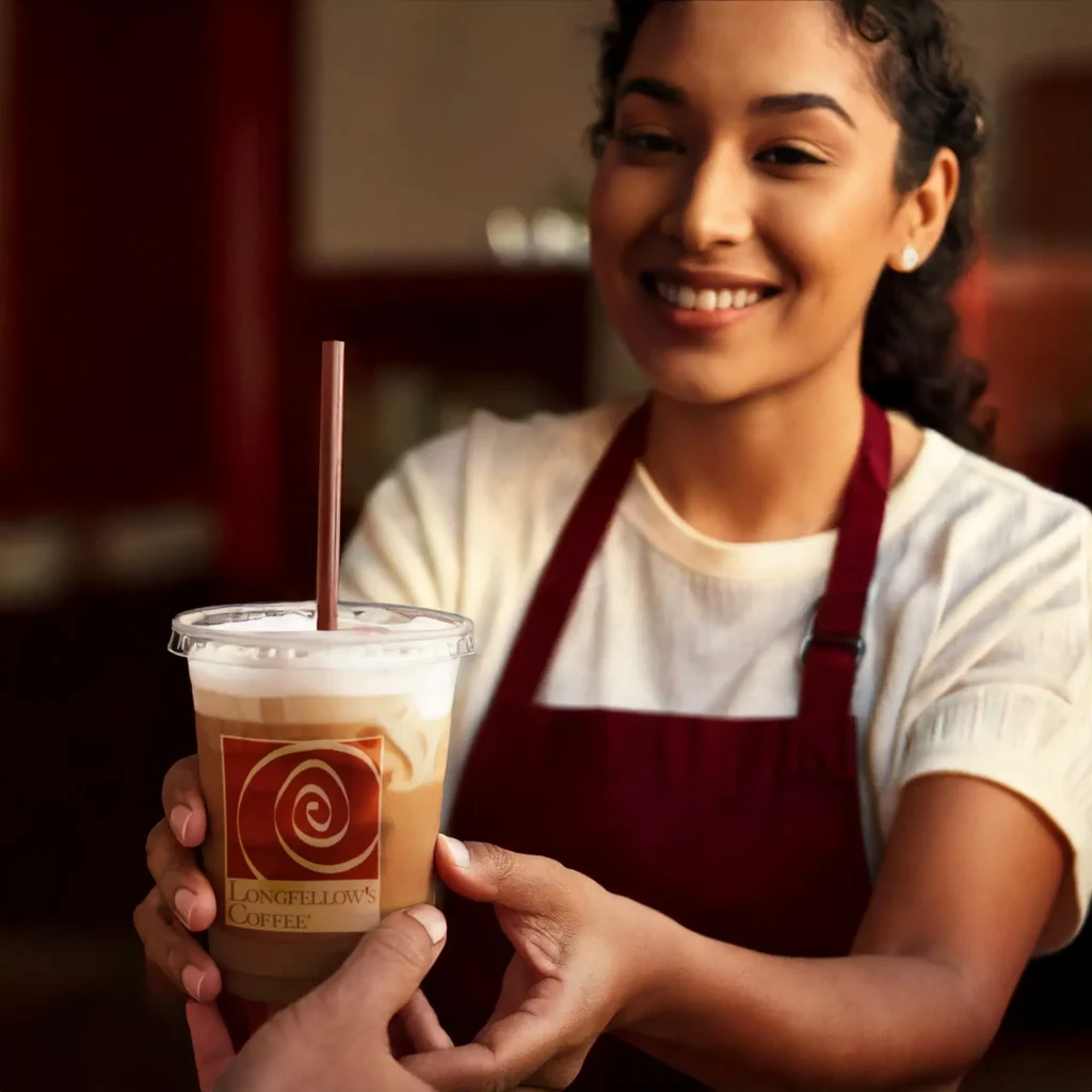 Friendly barista serving iced coffee at Longfellow’s Coffee café